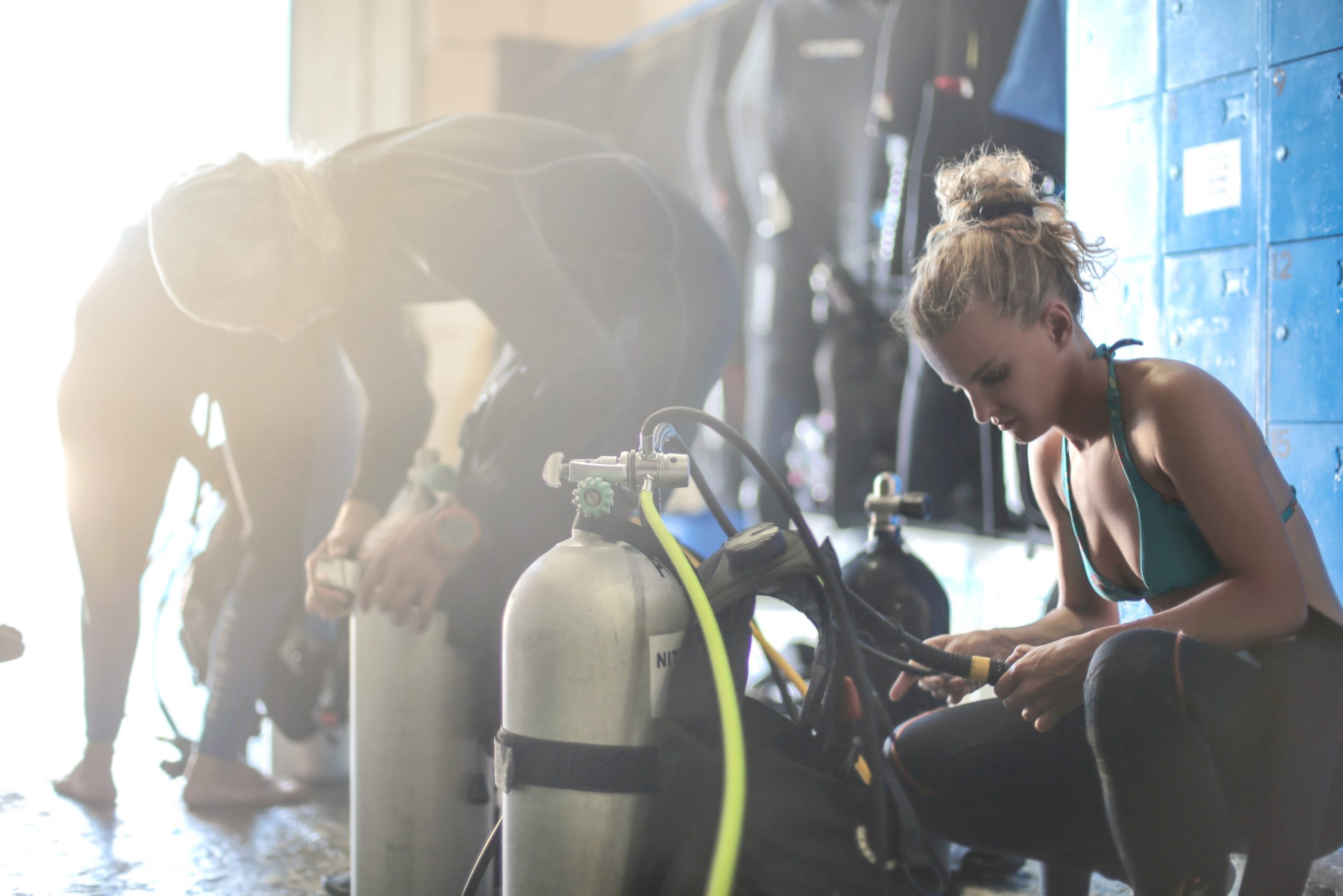 Three scuba divers dressing up for a dive session